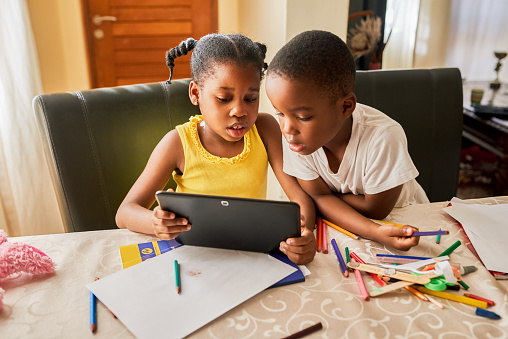 Cropped shot of two young siblings using a digital tablet while sitting at home