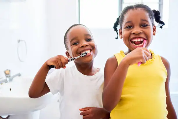 Cropped shot of two young siblings brushing their teeth in the bathroom at home