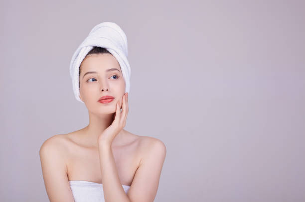 A young girl with a towel on her head, touches her face. stock photo