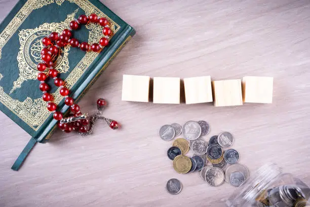 Flat lay composition of Qoran and Tasbih (prayer beads beads). The words on the Qoran is arabic character which means the Holy Qoran