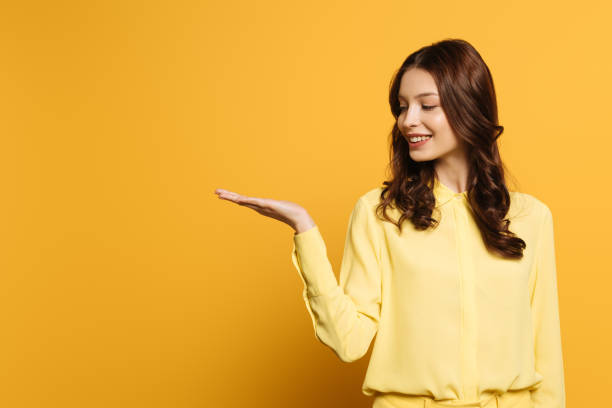 istock happy, attractive girl smiling while standing with open arm on yellow background 1211518140