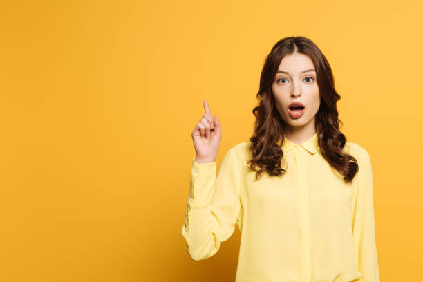 istock surprised girl showing idea gesture while looking at camera on yellow background 1211518153