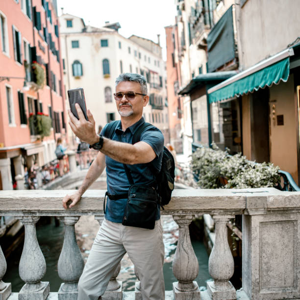 istock Senior bearded man smiling while taking selfie picture with mobile phone 1211521675