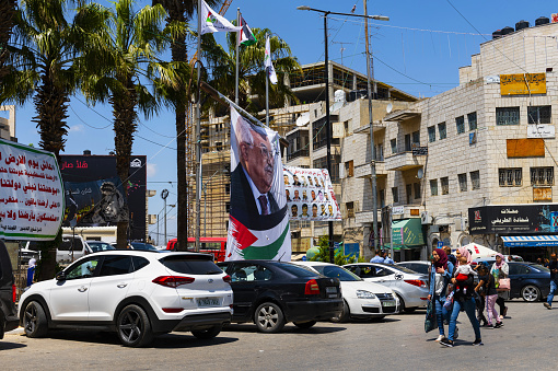OORamallah, Palestine, May 4, 2019: The people walk through the Al-Manara Square in the center of the city. On the big poster the President of the Palestinian Authority, Mahmoud Abbas, is pictured.