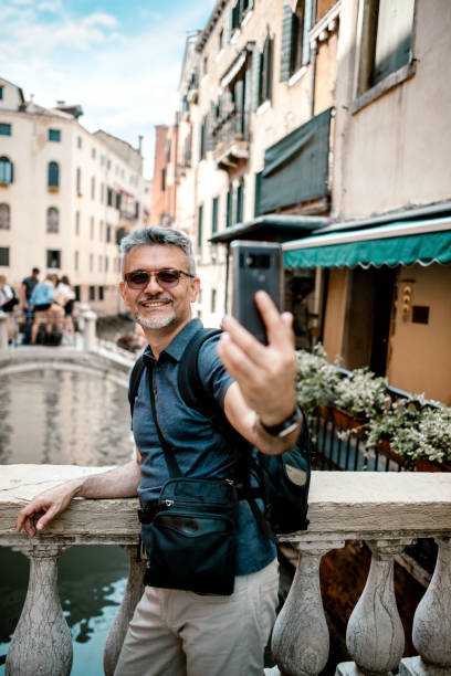 istock Senior bearded man smiling while taking selfie picture with mobile phone 1211522715