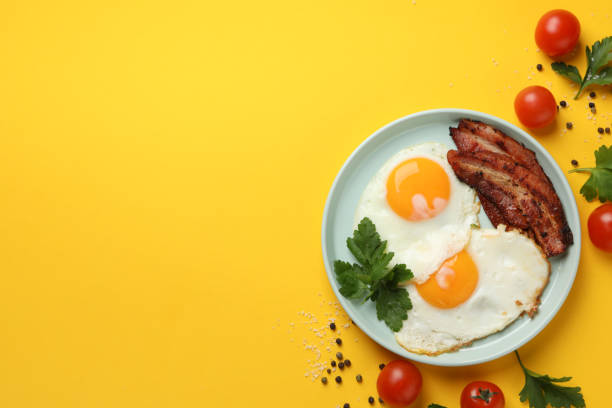 istock Delicious breakfast or lunch with fried eggs on yellow background, top view 1211525086