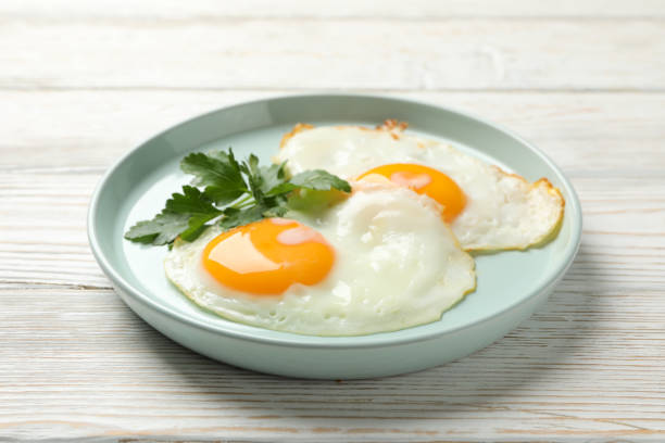 istock Plate with fried eggs on wooden background, close up 1211525513