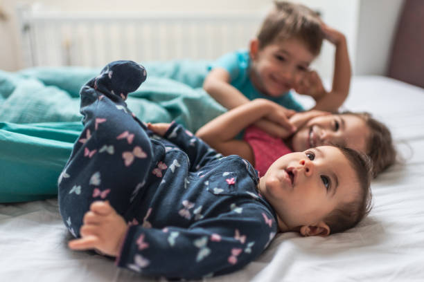 glückliche verspielte kinder im schlafzimmer - sibling brother family with three children sister stock-fotos und bilder