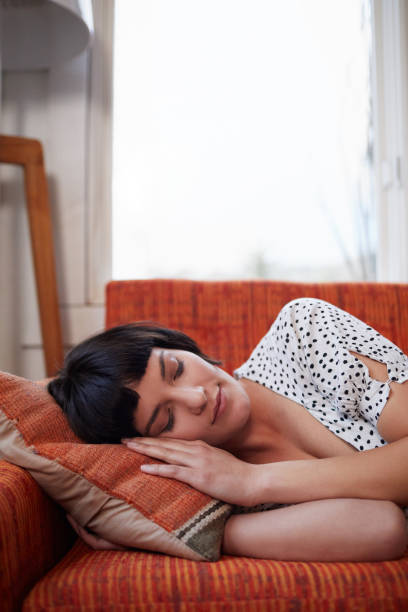 istock Young woman lying asleep on her sofa at home 1211532574