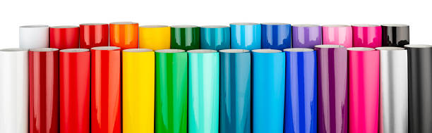 Row of various rainbow colored vinyl car wrapping or plotter cutting sticker plastic foil film rolls isolated white wide panorama banner background