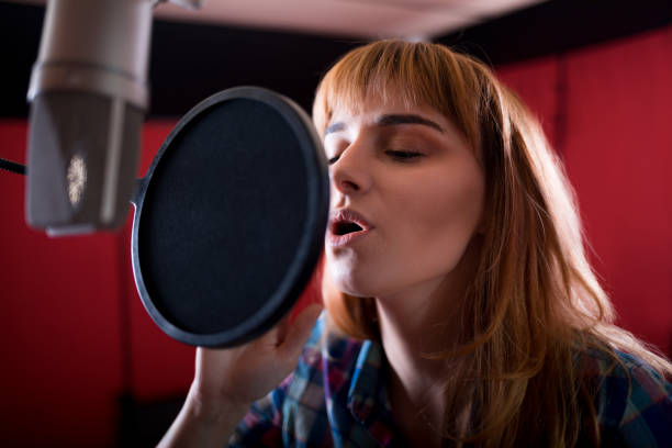 istock Female with microphone recording a voice for dubbing in music studio 1211538331