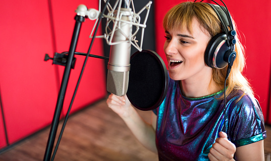 Mujer con micrófono grabando una voz para doblaje en estudio de música photo