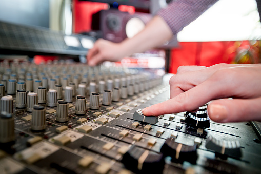 Music engineers working together in recording studio using mixing desk