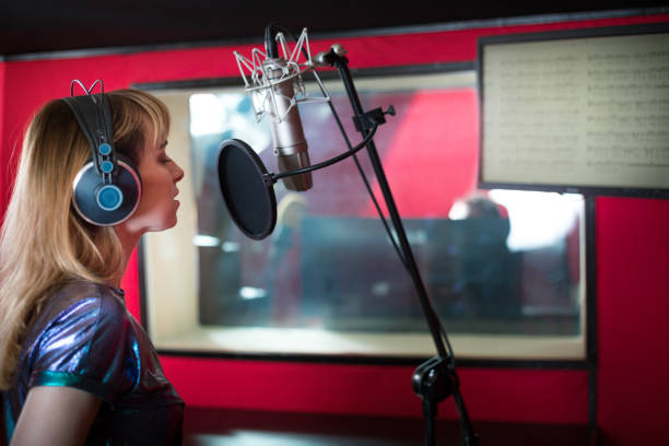istock Pretty female singer recording voice in sound studio 1211540049