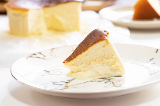 istock Basque Burnt Cheesecake on plate with piece of cake on white table background. 1211540434