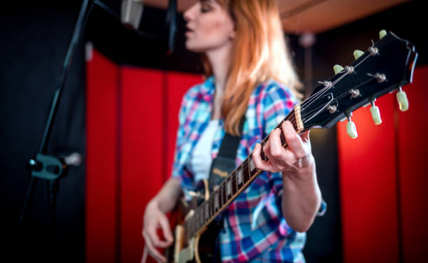 istock Young singer with guitar singing a song in recording studio 1211541324