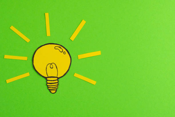 istock Composition with cut out paper, drawing light bulbs on a green background. Creative concept symbolizing the idea 1211544590