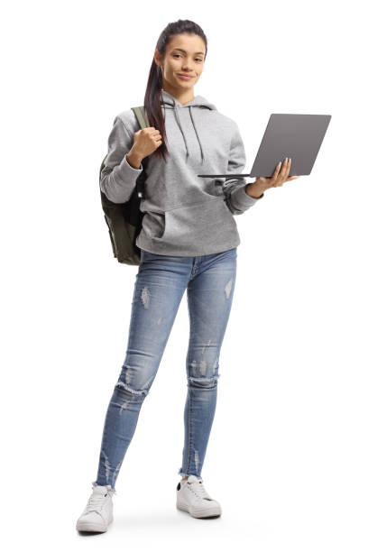 Female student with backpack holding a laptop computer and smiling at the camera Full length portrait of a female student with backpack holding a laptop computer and smiling at the camera isolated on white background women young women standing full length stock pictures, royalty-free photos & images