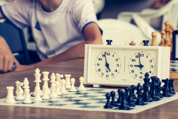 istock Chess board with chess pieces and clock on wooden desk 1211548955