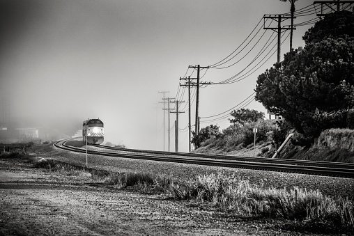 A locomotive of a commuter train traveling out of a fog bank in coastal Southern California.