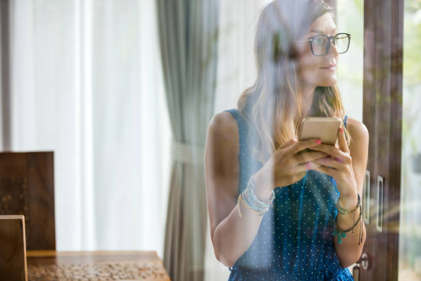 istock Young adult woman using smartphone in a modern home. 1211550112