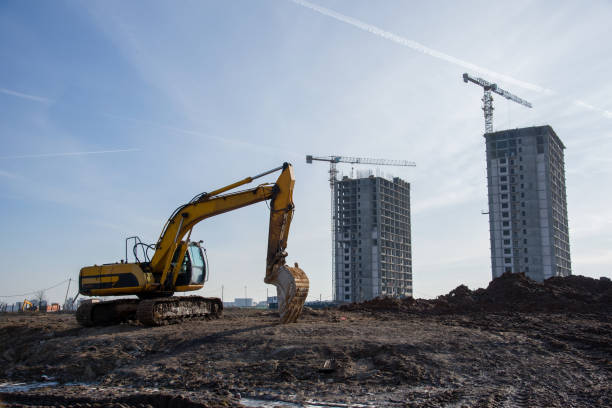 istock Excavator with bucket at large scale construction site on blue sky background 1211550618