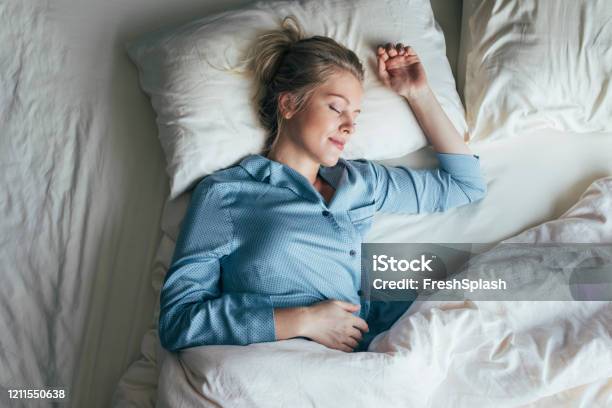 Sound Asleep Overhead Waist Up Shot Of A Pretty Blonde Woman In Blue Pyjamas Sleeping On A King Size Bed Stock Photo - Download Image Now