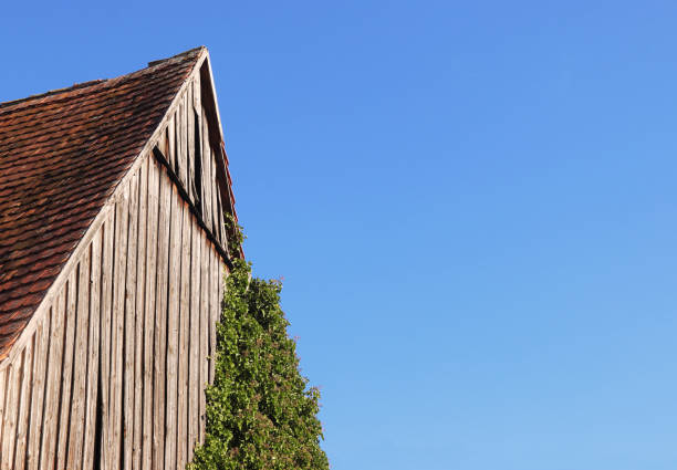 An old, wooden shed or shed. The shed has a simple design with large, solid doors and a thatched roof. The building is made of round logs butted together to form the walls.