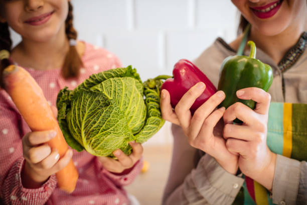 istock Mother and daughter in the kitchen holding vegetables. 1211551769