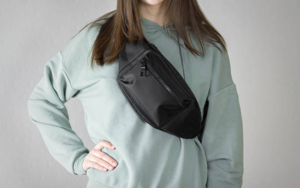 彼女の胸にバッグを持つパーカーの女の子。クローズアップ。灰色の背景で分離 - waist ストックフォトと画像
