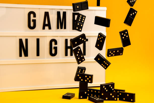 istock Game night text on lightbox with black dominoes on yellow background, table game 1211554670