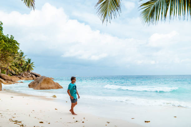 istock La Digue Seychelles,young man in casual clothes on the beach at Anse Source d'Argent, LA Digue Seychelles , near Praslin and Mahe Island 1211555986