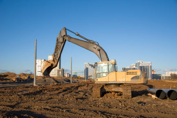 istock Excavator working at construction site. Backhoe digs ground for the foundation and for paving out sewer line 1211557898
