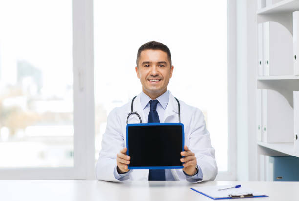 istock smiling male doctor showing tablet pc blank screen 1211557909