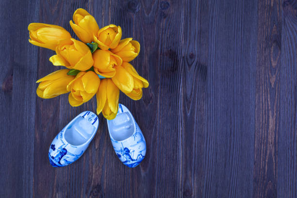paar clogs mit gelben tulpen bouquet. - cut flowers white small still life stock-fotos und bilder