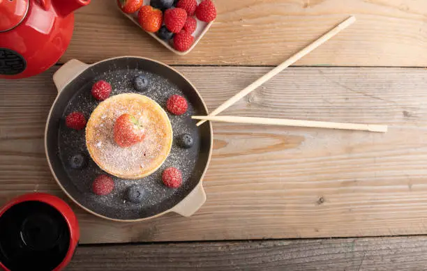 Homemade japanese hotcakes on a wooden background with raspberries, blackberries and strawberries and sugar powder.Top view.