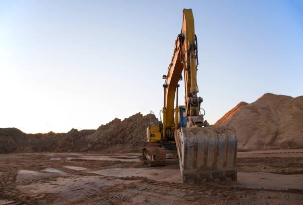 istock Excavator working at construction site. Backhoe digs ground for the foundation and for paving out sewer line 1211558980