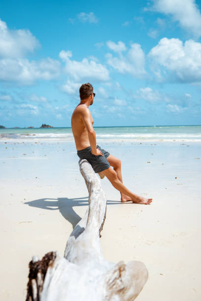 istock Praslin Seychelles,young men on tropical beach with palm tree, white beach man walking Seychelles Island, tanning men on tropical vacation 1211559163