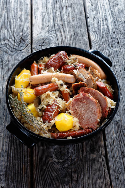 piatto della regione francese dell'alsazia choucroute garnie di cavolo fermentato con pancetta affumicata, lombo di maiale, salsicce stufate in vino bianco con cipolla, aglio e spezie - sausage knackwurst food bratwurst foto e immagini stock