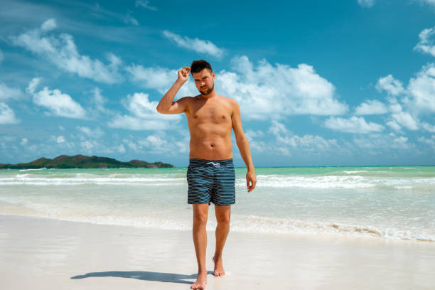 istock Praslin Seychelles,young men on tropical beach with palm tree, white beach man walking Seychelles Island, tanning men on tropical vacation 1211562032