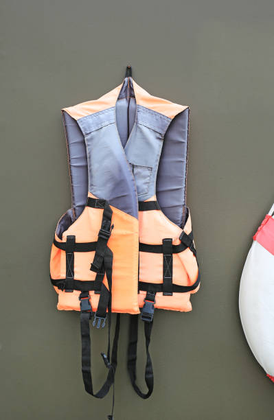 istock Orange color life jackets hanging on the gray wall background. 1211563543