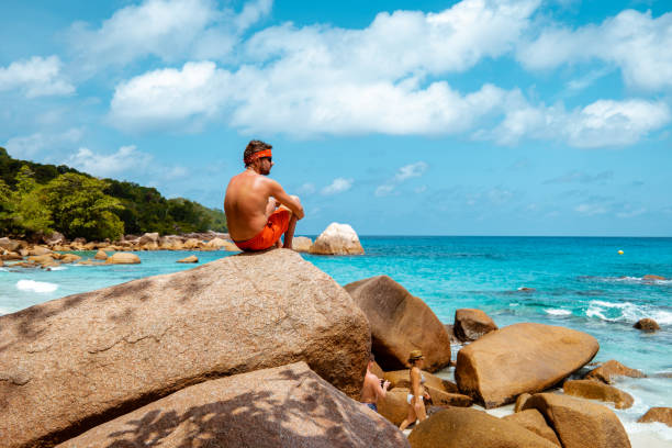 istock Praslin Seychelles,young men on tropical beach with palm tree, white beach man walking Seychelles Island, tanning men on tropical vacation 1211564862