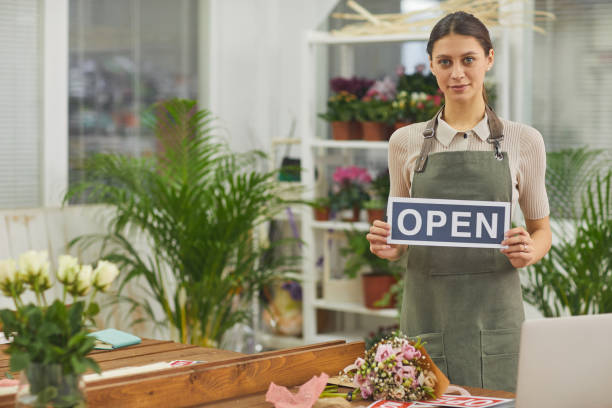 женщина холдинг открытый знак в цветочном магазине - owner florist sign business стоковые фото и изображения