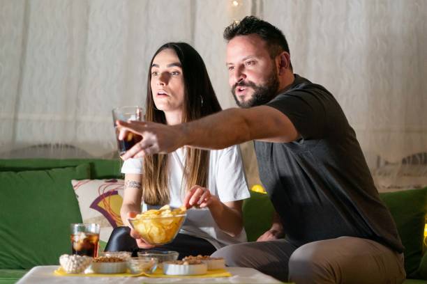 istock young couple watching tv at home 1211565220