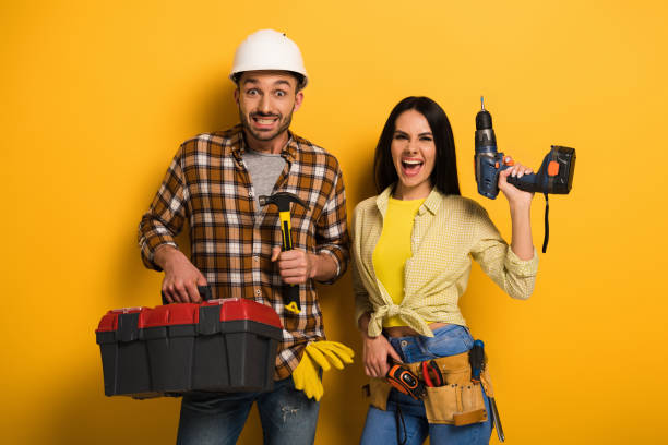 excited manual workers holding toolbox and electric drill on yellow excited manual workers holding toolbox and electric drill on yellow woman wearing tool belt stock pictures, royalty-free photos & images