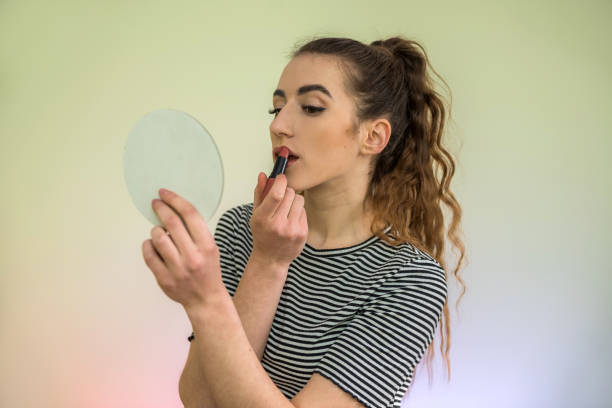 istock beautiful brunette girl using pink lipstick doing makeup morning before work isolated on green 1211567877