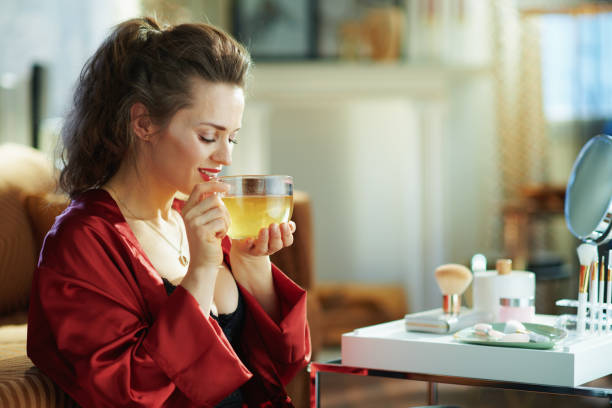 femme avec la tasse de thé vert dans le salon moderne dans le jour ensoleillé - the human body photos et images de collection