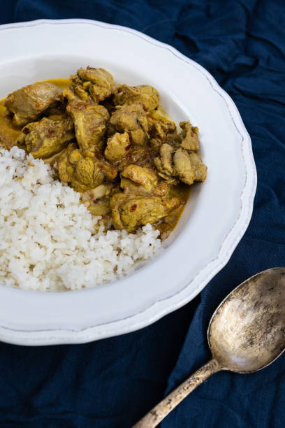 istock Orange spicy chicken curry and white basmati rice in a white plate on a dark blue background. Indian traditional cuisine 1211576379
