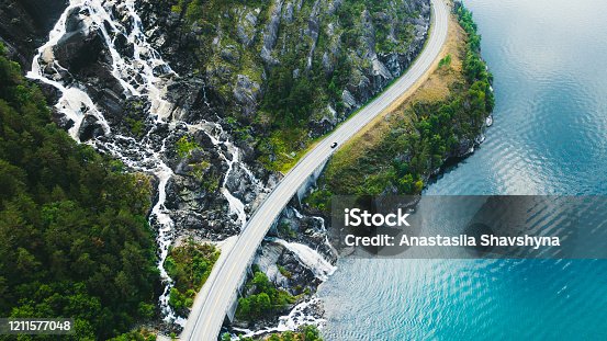 istock Aerial view of scenic mountain road with car, sea and waterfall in Norway 1211577048