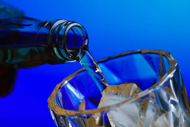 istock Pouring whiskey from bottle into glass with ice 1211577848
